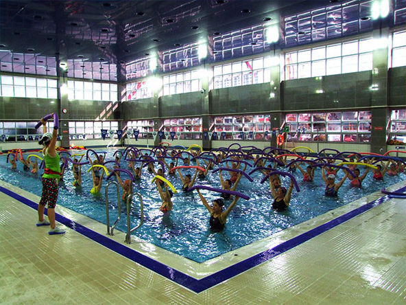 실내 수영장에서 단체로 아쿠아로빅을 배우는 사진